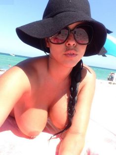 Femme nue: Une jolie beurette se prend en selfie sur la plage les seins nus et piercés